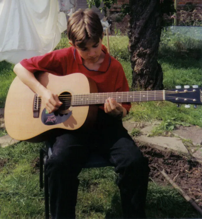 Martin Tomkins as a young guitarist with an acoustic guitar